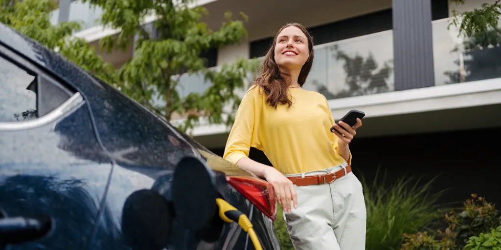 woman using smartrphone while charging her electric car