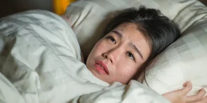 young sleepless beautiful and scared Asian Chinese woman lying on bed awake at night